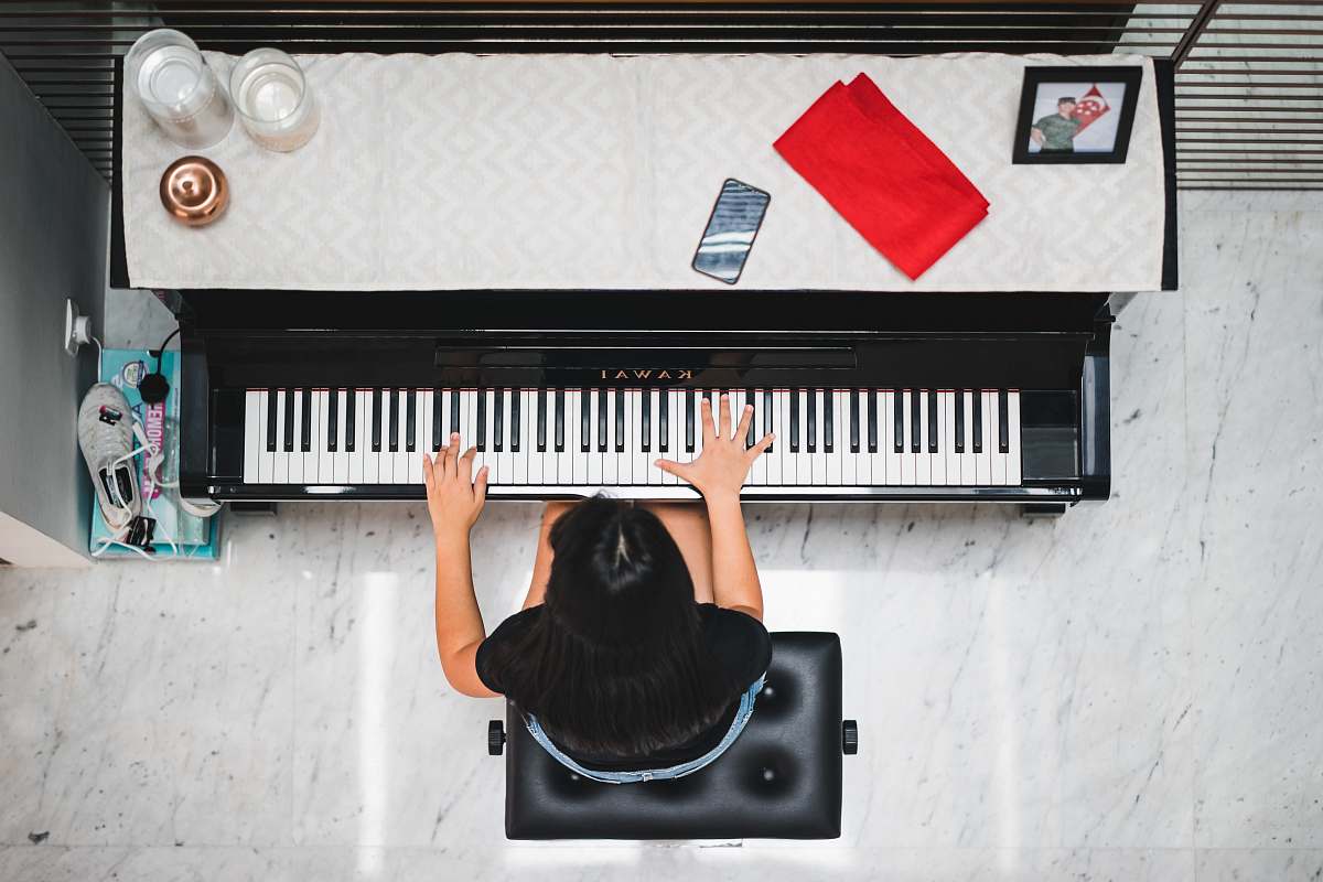 music woman playing piano near white wall inside room piano